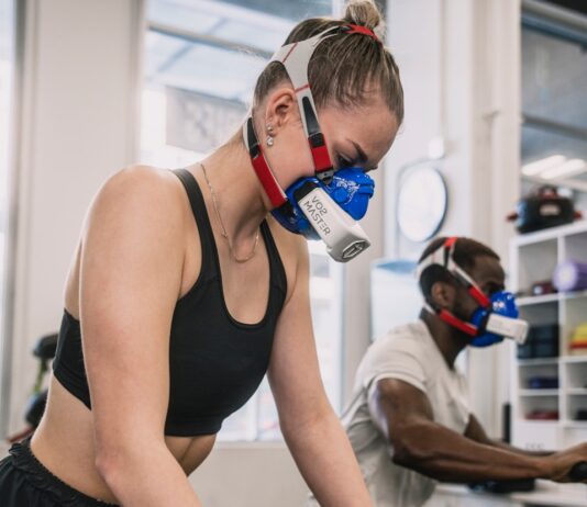 “근육 건강, 일상 속 작지만 강한 변화로 챙긴다” a woman wearing a gas mask while riding a stationary bike