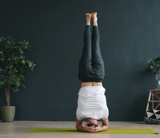 역립 요가: 세상을 거꾸로 보는 용기, 머리 서기 도전 Woman performing a headstand yoga pose indoors.